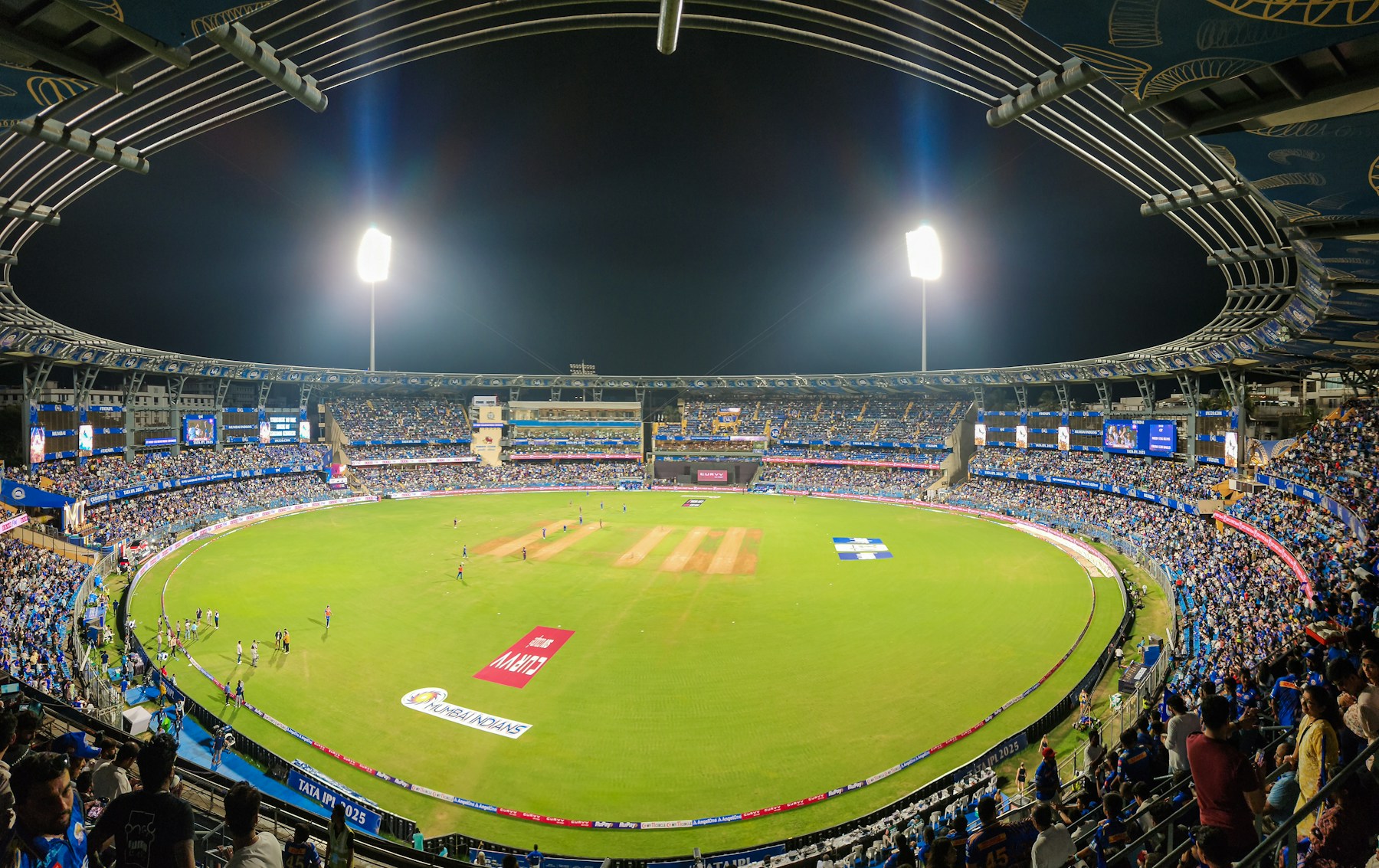 A packed cricket ground under floodlights